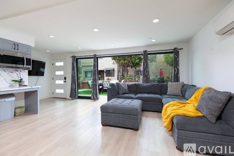 A modern living room with a grey sofa and a wooden floor.