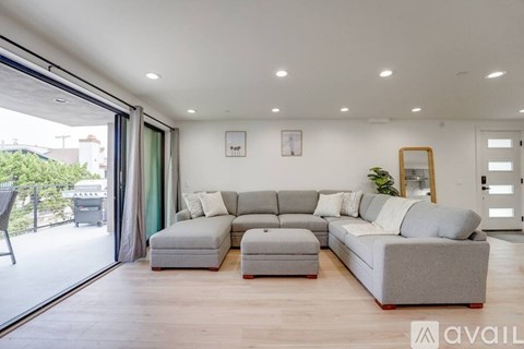 A modern living room with a grey sofa set and a wooden floor.