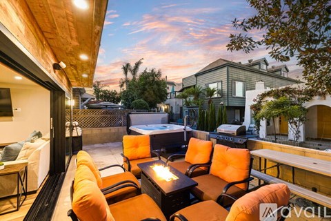A hot tub is in the foreground of a house with a balcony.