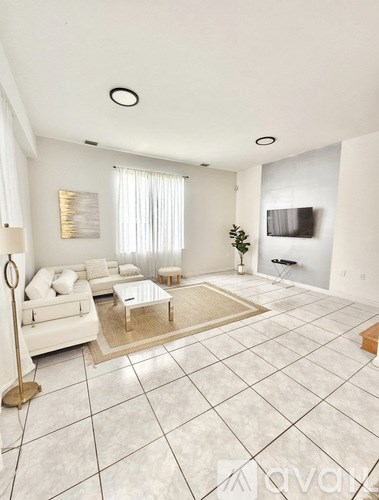 A living room with a white couch and a glass coffee table.