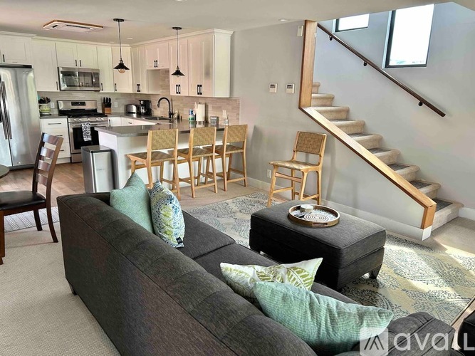 A living room with a grey couch and wooden chairs.