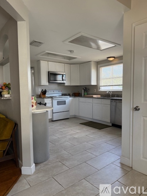 A kitchen with white cabinets and a white stove top oven.