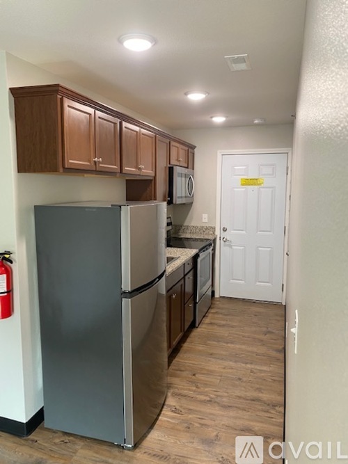 A kitchen with a refrigerator, cabinets, and a door.