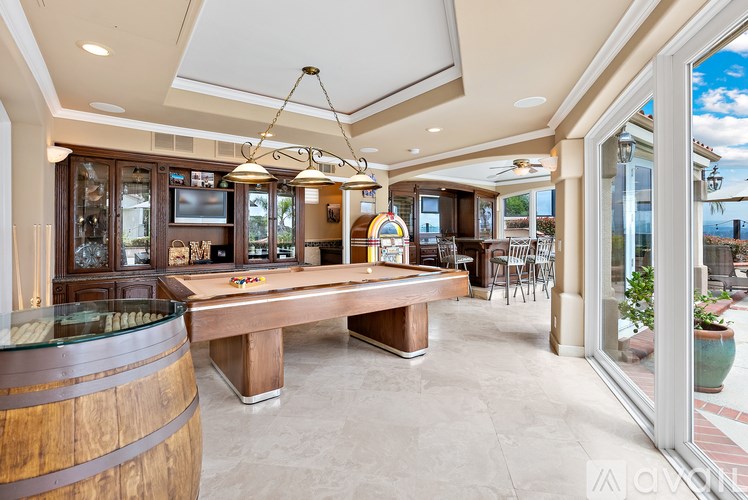 A large wooden table is in the middle of a room with a barrel table.