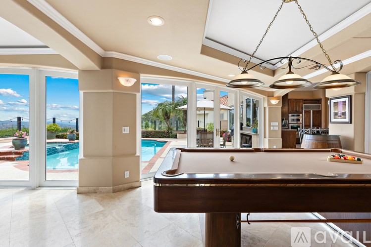 A billiard table is in the middle of a room with a pool table and a view of the outdoors.