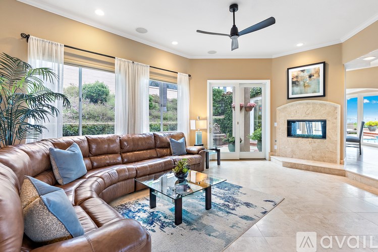 A living room with a brown leather couch and a glass coffee table.