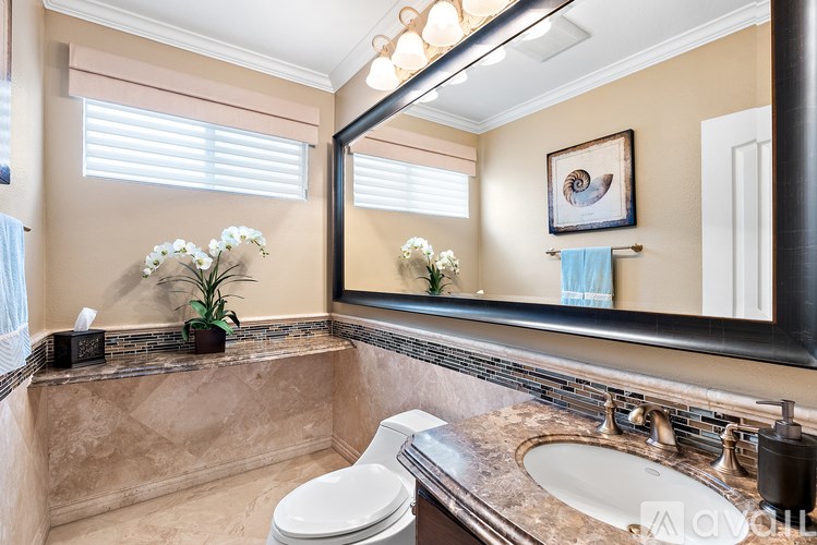 A bathroom with a toilet, sink, and mirror.