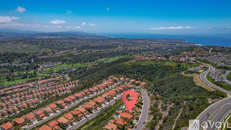 A bird's eye view of a residential area with a road and a red pin marking a specific location.