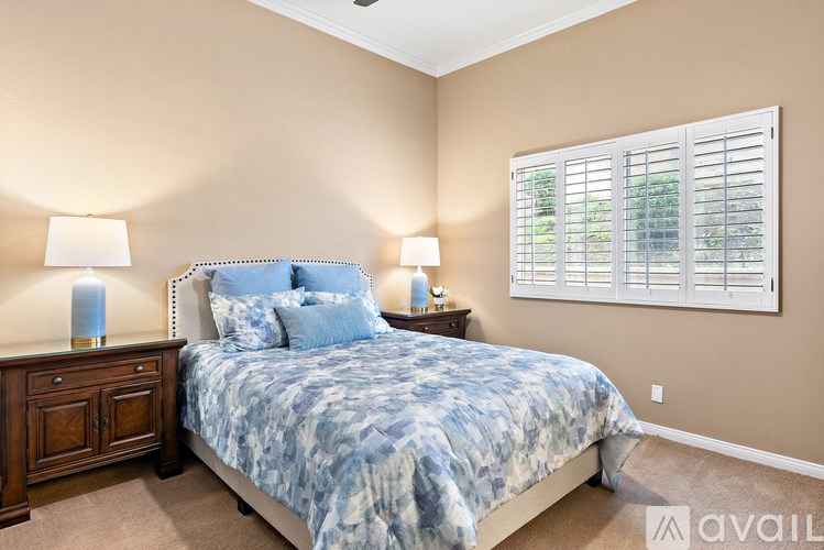 A bedroom with a bed, nightstands, and a window with blinds.
