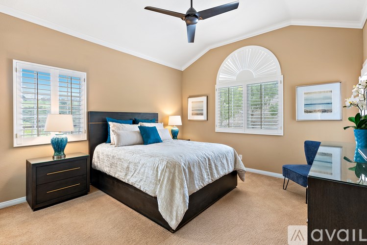 A bedroom with a bed, a ceiling fan, and a window with blinds.