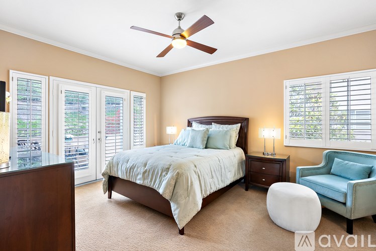 A bedroom with a bed, chair, and ceiling fan.
