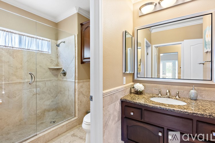 A bathroom with a glass shower stall and a marble countertop.