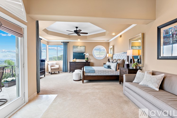 A well-lit, spacious bedroom with a large bed and a balcony overlooking the ocean.