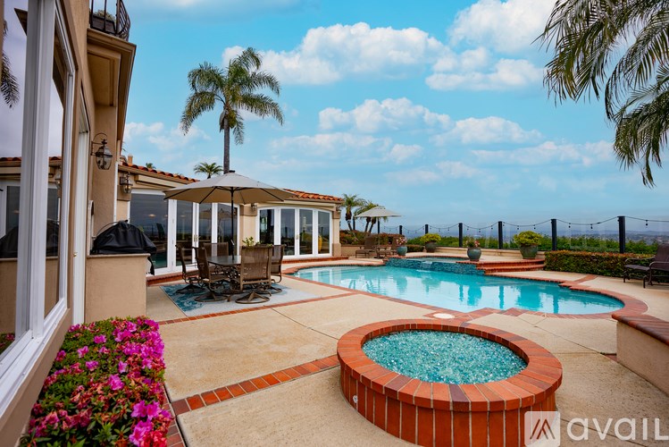 A pool with a hot tub and a patio with chairs and a table.