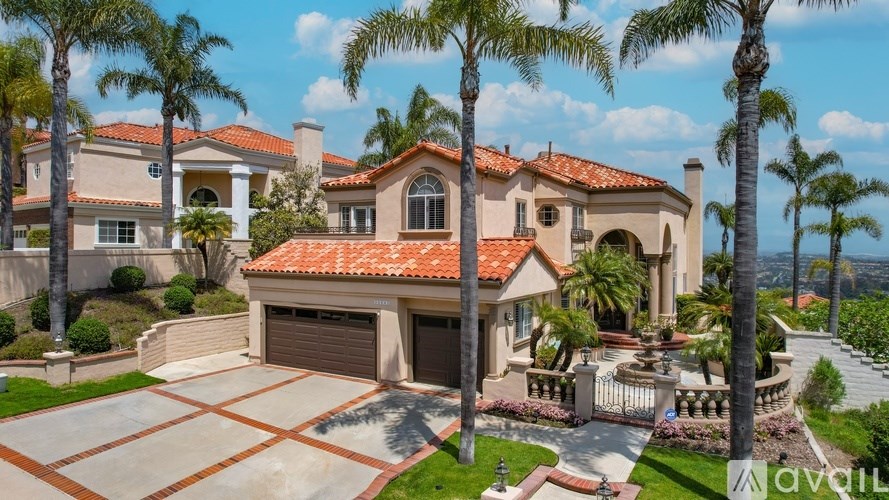 A large house with a red tile roof and a driveway in front.