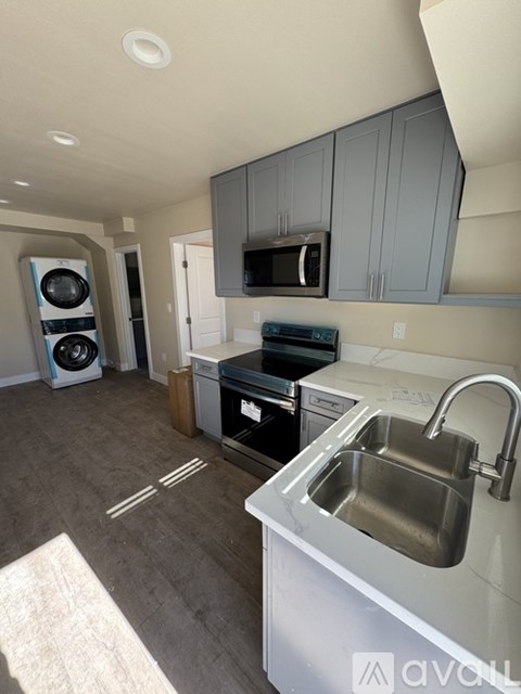 A kitchen with a sink, stove, and microwave.