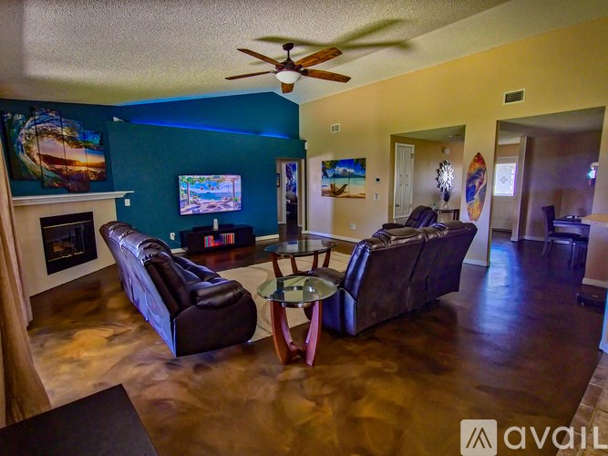 A living room with a brown leather couch and a ceiling fan.