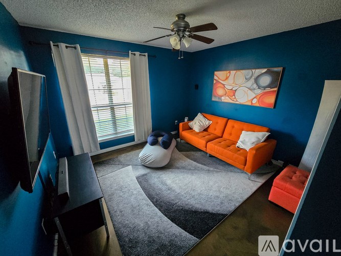 A living room with a blue wall and a ceiling fan.