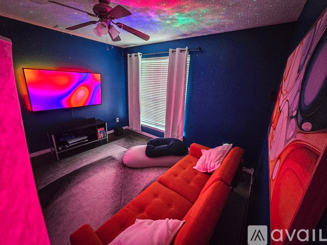 A room with a red couch and a ceiling fan with lights.