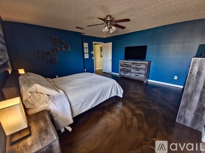 A bedroom with a bed, dresser, and ceiling fan.