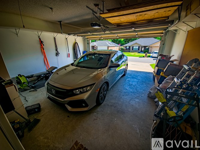 A car is parked in a garage with a tool hanging on the wall.