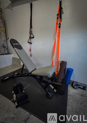 A gym with a bench, weights, and resistance bands.