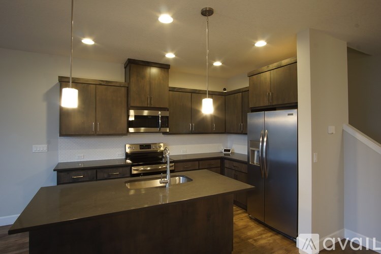 A modern kitchen with dark brown cabinets and stainless steel appliances.