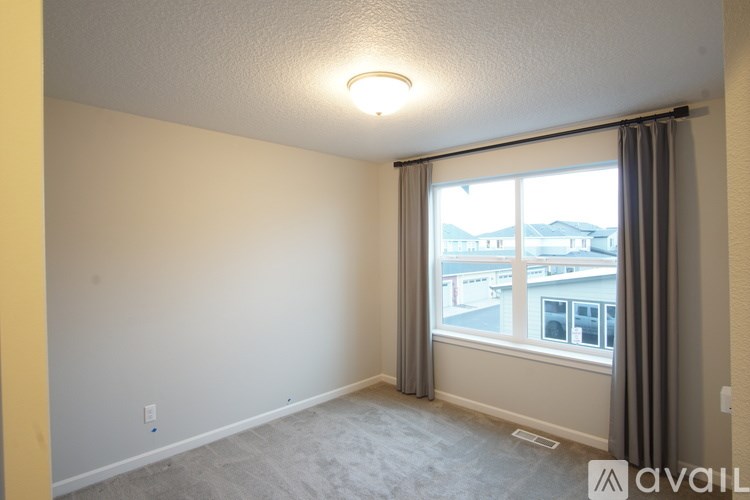 A room with a window and a view of buildings outside.