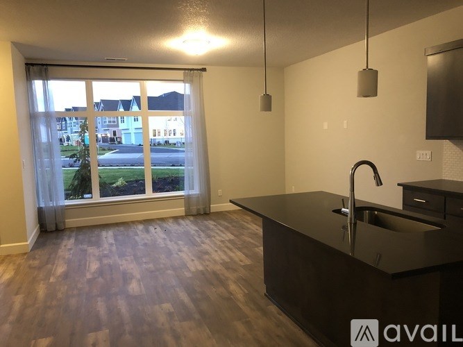 A kitchen with a black countertop and a large window overlooking a residential area.