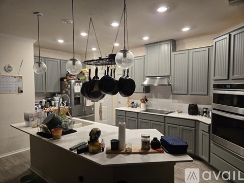 A kitchen with a white island and grey cabinets.