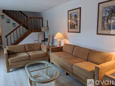 A living room with a tan couch and a glass coffee table.