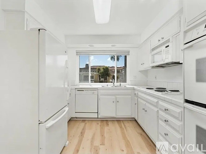 A white kitchen with wooden floors and white appliances.