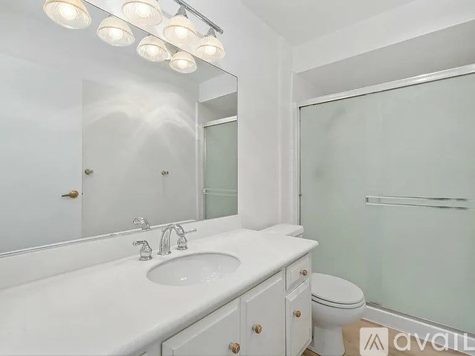 A white bathroom with a sink, toilet, and mirror.