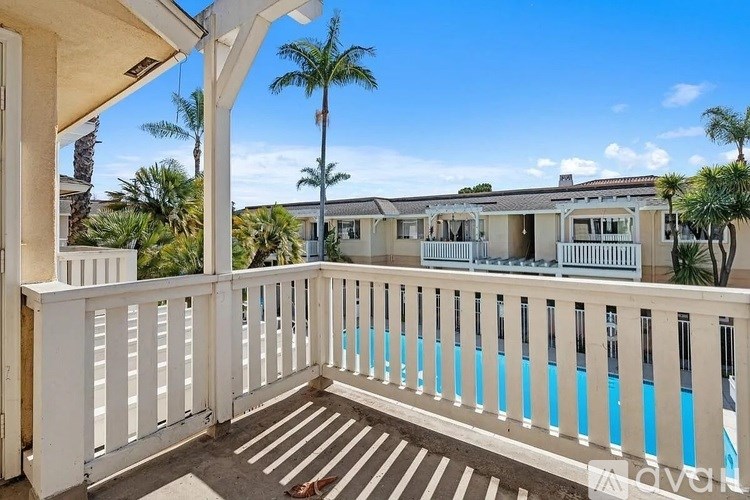 A balcony with a pool and palm trees in the background.