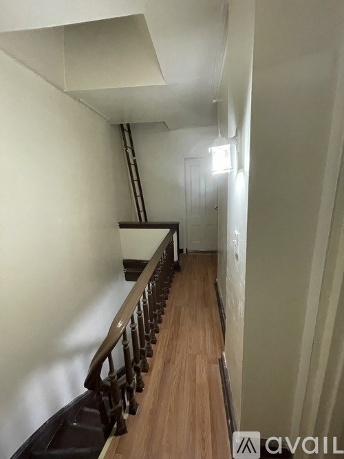 A hallway with a wooden floor and a metal railing.