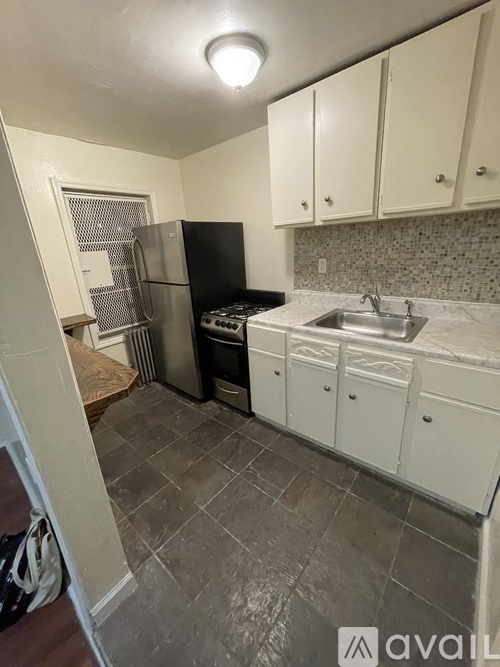 A kitchen with white cabinets and a black fridge.