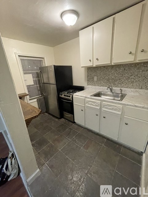 A kitchen with white cabinets and a black fridge.