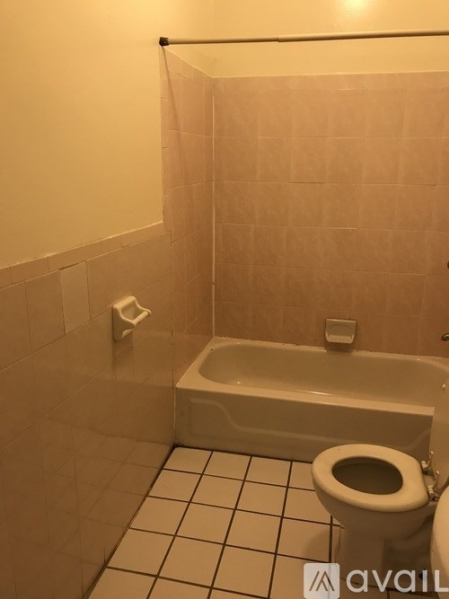 A bathroom with a toilet, tub, and tiled floor.