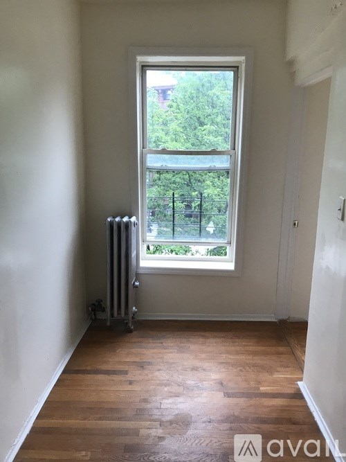 A room with a window and a radiator on the floor.