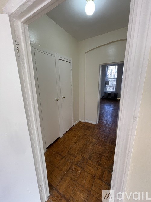 A hallway with wooden floors and white walls.