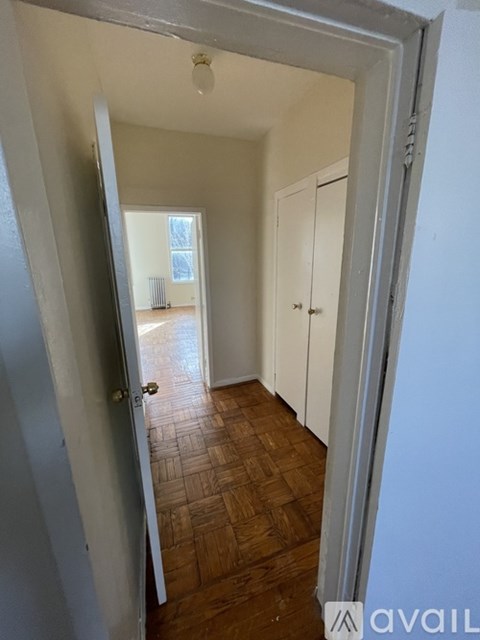 A hallway with a wooden floor and white walls.