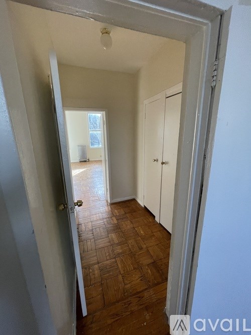 A hallway with a wooden floor and white walls.