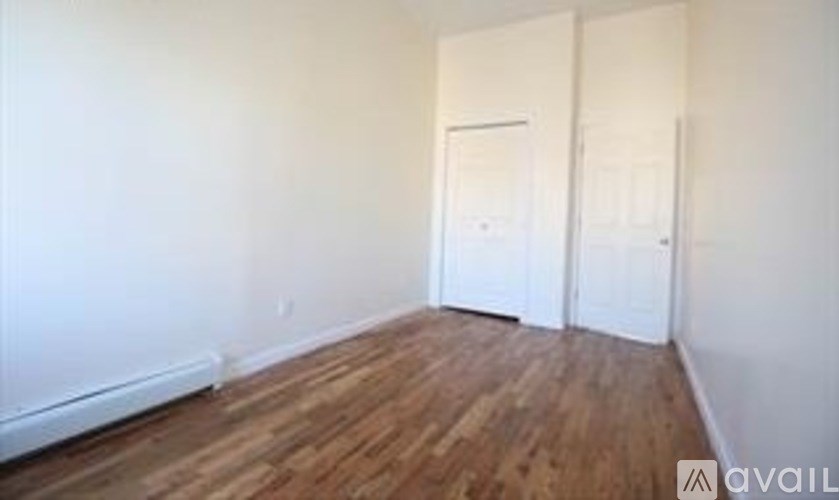 A room with wooden floors and two white doors.