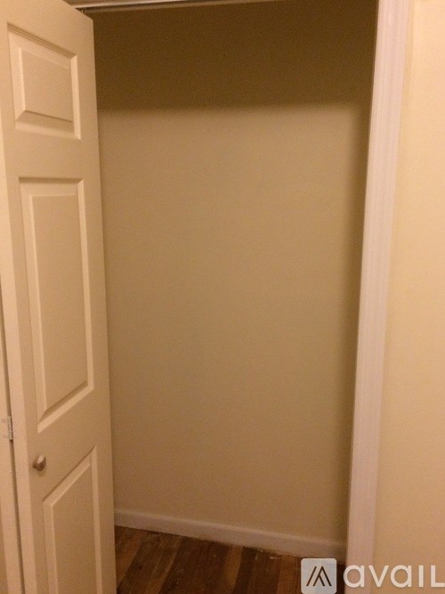 A white door is open to a room with a wooden floor.