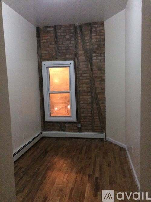 A room with a window and a brick wall.
