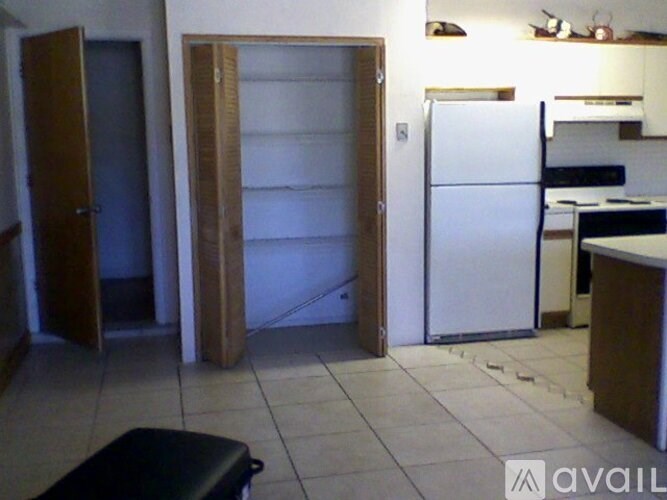 A kitchen with a refrigerator, a stove, and a door that is open.