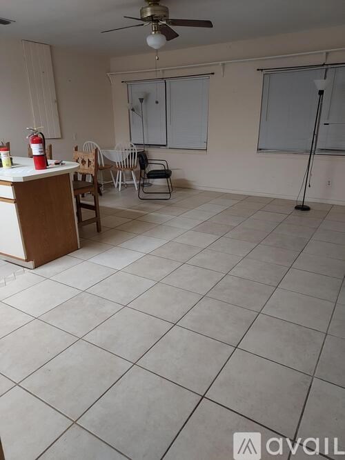 A room with a ceiling fan and a table with chairs.