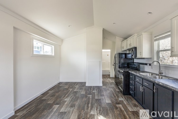 A kitchen with black cabinets and a wooden floor.