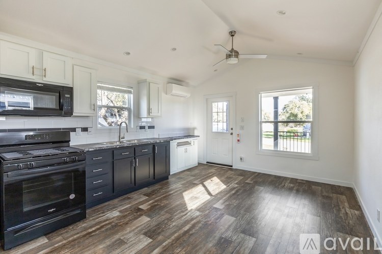A kitchen with dark wood floors and white walls.