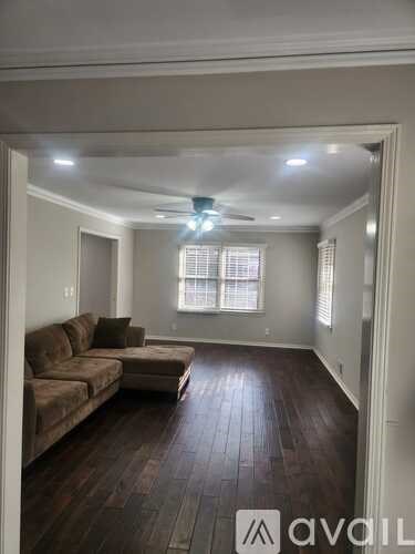 A living room with a brown couch and wooden floors.